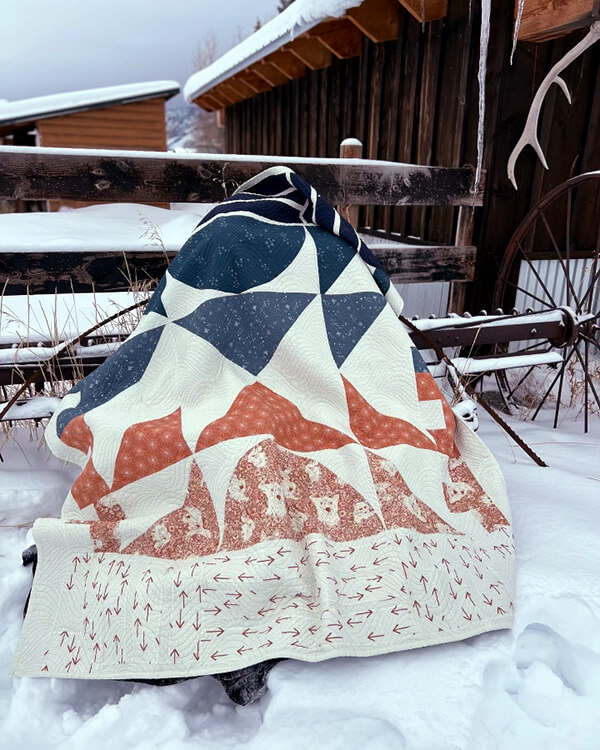 Quilt outside by a barn in the snow